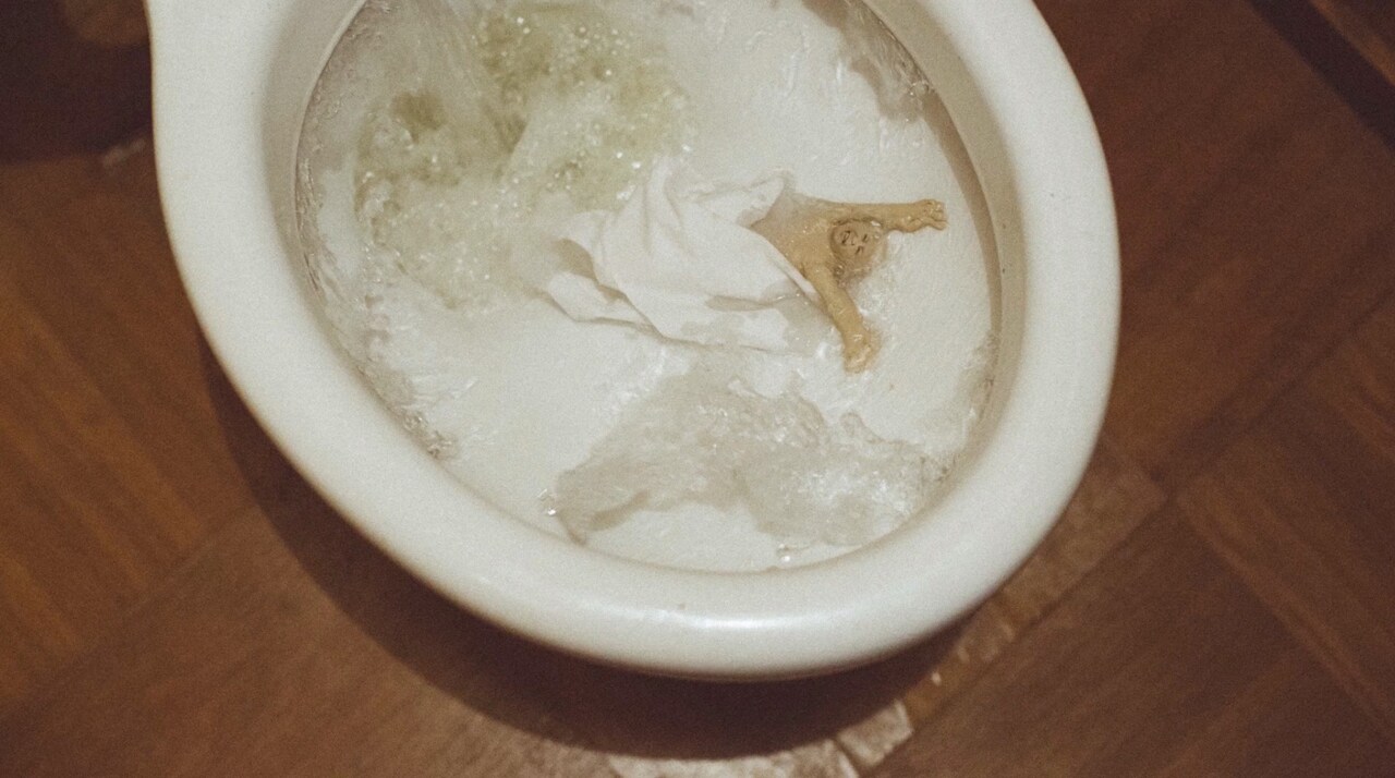 クリトリック・リス「陽の当たらぬ部屋」ミュージックビデオより、トイレで流されるスギム。