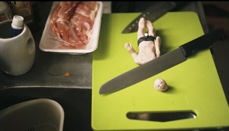 クリトリック・リス「陽の当たらぬ部屋」ミュージックビデオより、包丁で斬首されるスギム。