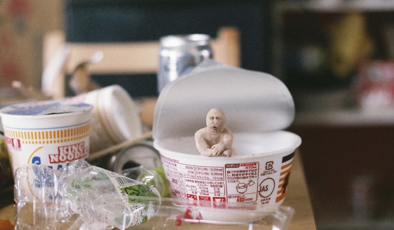 クリトリック・リス「陽の当たらぬ部屋」ミュージックビデオより、カップ麺の容器に入るスギム。