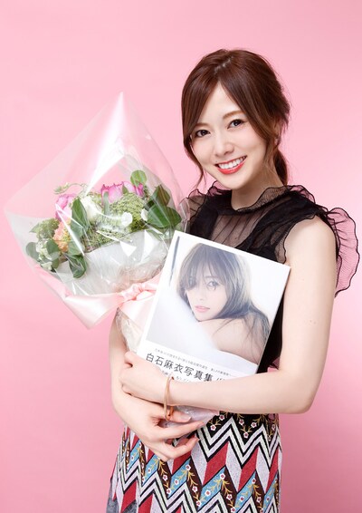 花束と「パスポート」を抱えて笑みを浮かべる白石麻衣（乃木坂46）。