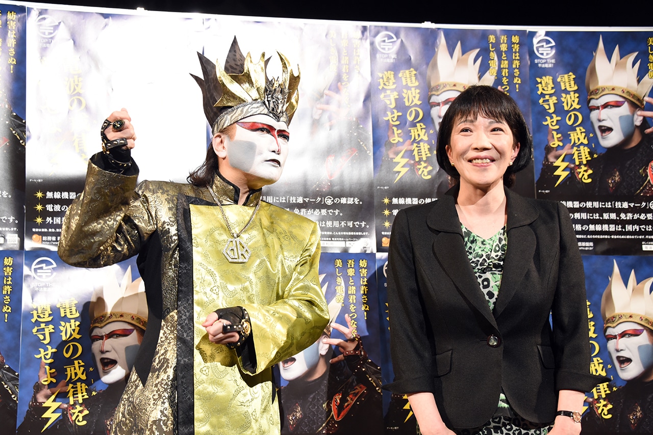 エアドラムを叩くデーモン閣下と高市早苗総務大臣。