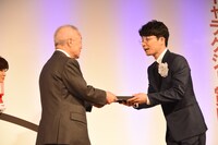 橋本隆氏から盾を受け取る星野源（右）。