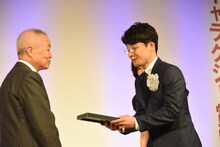 橋本隆氏から盾を受け取った星野源（右）。