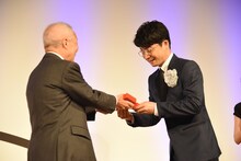 橋本隆氏からトロフィーを受け取る星野源（右）。
