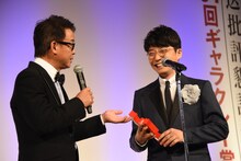 横山雄二アナウンサーからお祝い金の金額が少ないことを指摘され苦笑いを浮かべる星野源（右）。