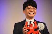 トロフィーを両手で持つ星野源。