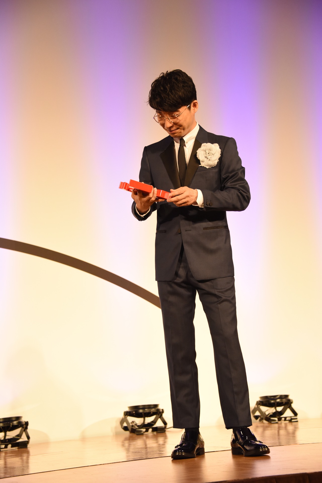 うれしそうにトロフィーを見つめる星野源。