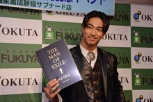 「THE MAN OF EXILE AKIRA 2006-2016」を持ち微笑むEXILE AKIRA。