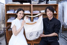 スノービューティー「#雪に願いを」キャンペーン賞品のサイン入りランドリーバッグを持つ武井咲（左）、高橋一生（右）。