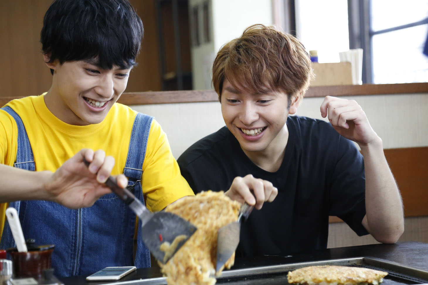 お好み焼きを返すユースケと見守るコーイチ。
