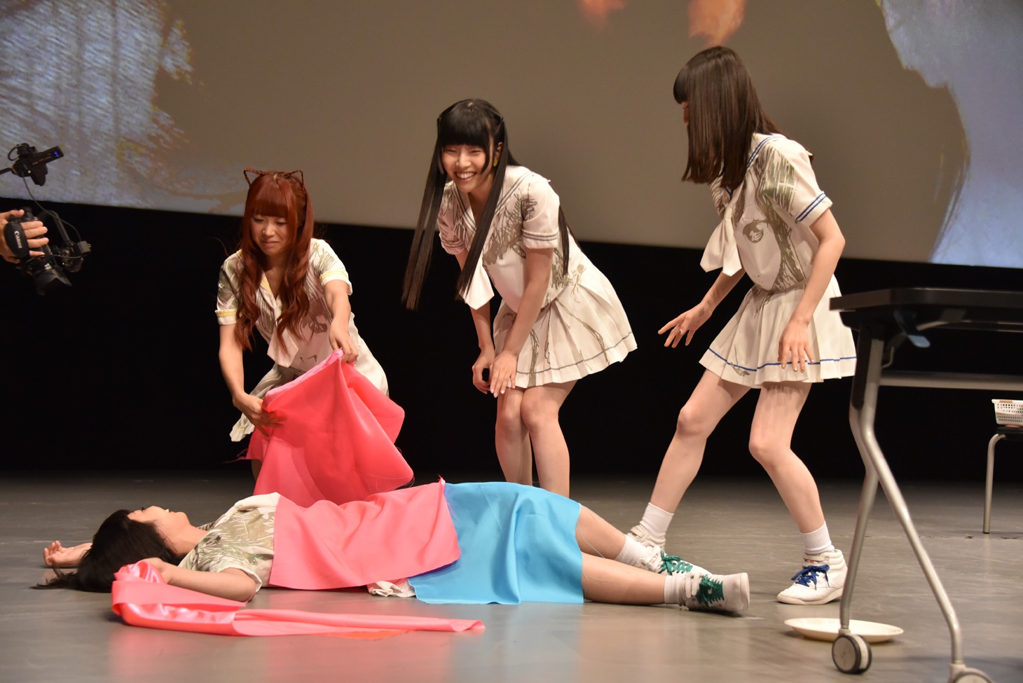 倒れた夢眠ねむにテーブルクロスをかけて“埋葬”するでんぱ組.incメンバー。