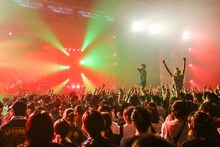 フロアに控えるたなしんたなしん（B, Cho / グッドモーニングアメリカ）にビールをもらいに行く柴田隆浩（Vo, G / 忘れらんねえよ）。（撮影：安藤みゆ）