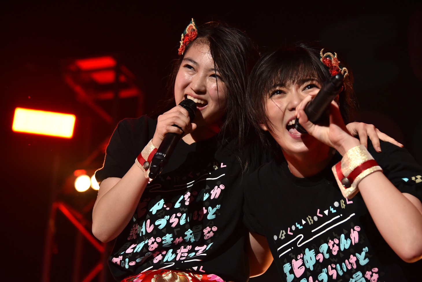 肩を組んで歌う柏木ひなた（左）と安本彩花（右）。