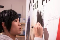 パネルにサインを入れる朴ウィト。