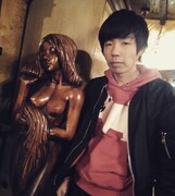 女性の像と映る吉田靖直(右)。