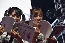 むすびーズからプレゼントされた冊子をうれしそうに眺める宮島るりか（左）と椎名エル（右）。