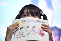 むすびーズからプレゼントされた冊子を持った宮島るりか。