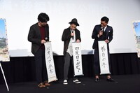 MCに「字がきれいですね」と褒められ、互いの書き初めを見合う登壇者たち。