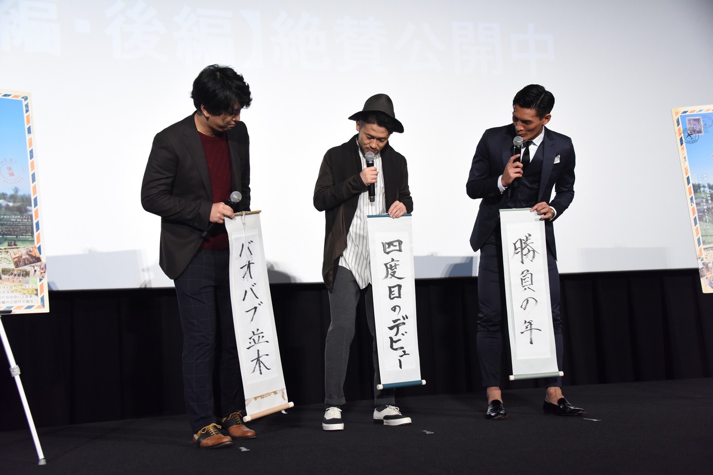 MCに「字がきれいですね」と褒められ、互いの書き初めを見合う登壇者たち。