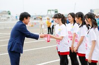 新潟商工会議所の福田勝之会頭からたすきを受け取るNGT48のメンバーたち。