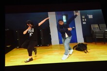 荻野目洋子「ダンシング・ヒーロー」を踊る柏木ひなた（左）と“校長”こと藤井ユーイチマネージャー（右）のコント映像。