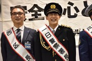 一日警察署長の襷をかけてもらい、照れ笑いを浮かべるユースケ(右)。