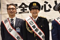 一日警察署長の襷をかけてもらい、照れ笑いを浮かべるユースケ（右）。