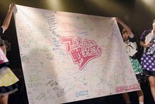 ステージ上でファンからの寄せ書きを広げるA応P。