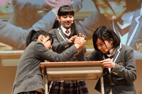 腕相撲をする日高麻鈴と新谷ゆづみ。レフェリーは白鳥沙南。