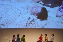 砂に埋もれるユースケを見るメンバー。