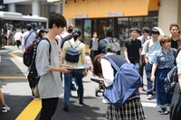 謝罪本を配布する女子高校生。