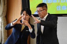 佐竹敬久秋田県知事（右）にGポーズを教えるユースケ（左）。