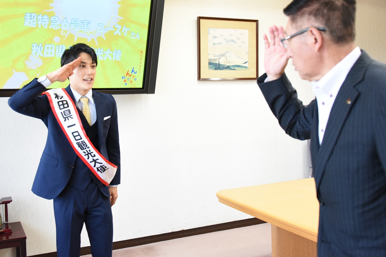 敬礼で佐竹敬久秋田県知事（右）を送り出すユースケ（左）。