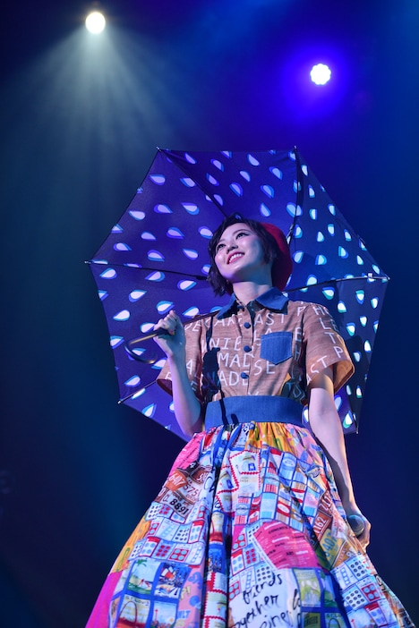青い傘を手に「Rain」を歌う安本彩花。