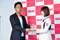 株式会社レコチョクの執行役員・柴崎栄太郎氏（左）よりトロフィーを受け取る佐々木美玲（右）。