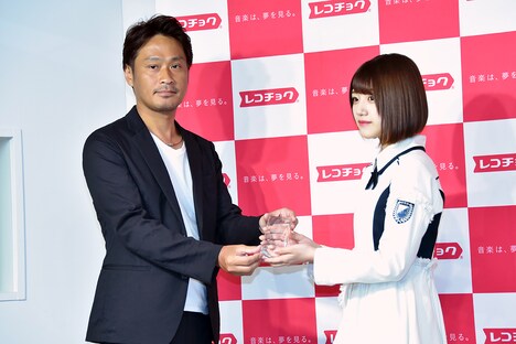 株式会社レコチョクの執行役員・柴崎栄太郎氏（左）よりトロフィーを受け取る佐々木美玲（右）。