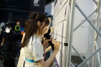 移動中にサインをする齋藤飛鳥。