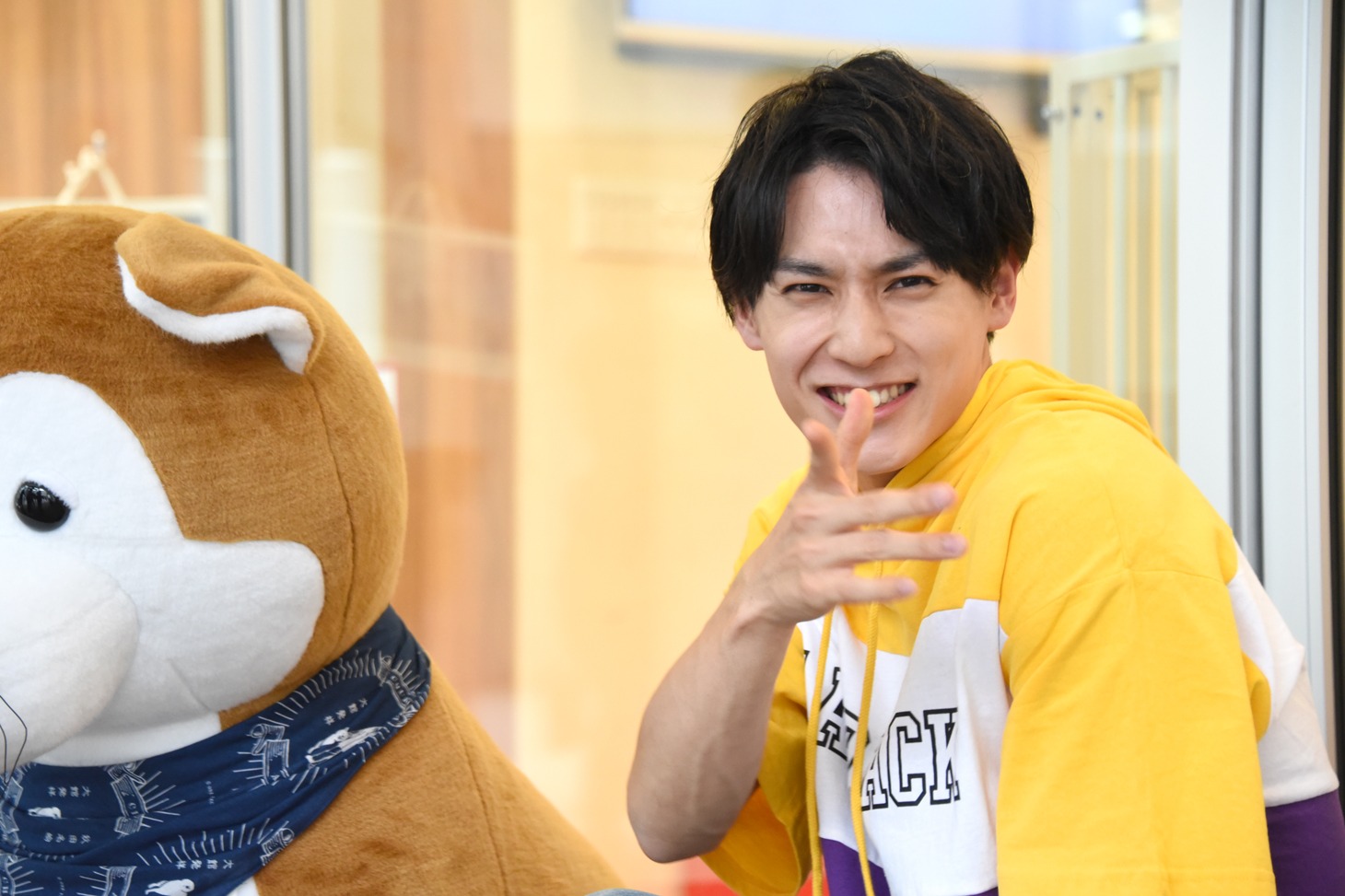 施設のアナウンス音で本番の撮影が中断してしまい、笑みを浮かべるユースケ（超特急）。