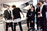 「NYLON」誌面に掲載されるカットを再現するカイとユーキにガヤを入れるメンバー（右）。