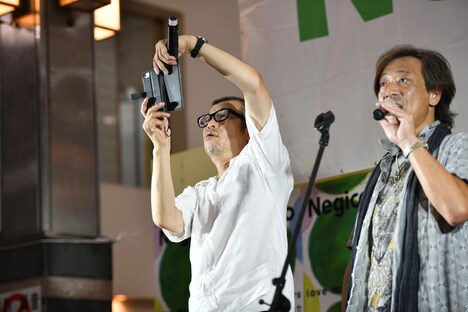 商店街の光景を写メに収める熊倉マネージャー（左）。