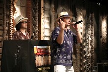 スモーキー・テツニ（左）と共に実演販売を行う横山剣（右）。（写真提供：ユニバーサルシグマ）