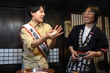 ハイテンションにごはんを丸めるユースケ（左）と、彼の勢いに気圧され気味の「秋田長屋酒場」店長（右）。