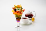 京橋千疋屋フルーツパーラーで提供される「“八月の夢”福耳レインボーフルーツパフェ」とドリンクのセット。
