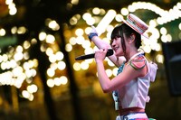 回転するメリーゴーランドの横で歌う小倉唯。