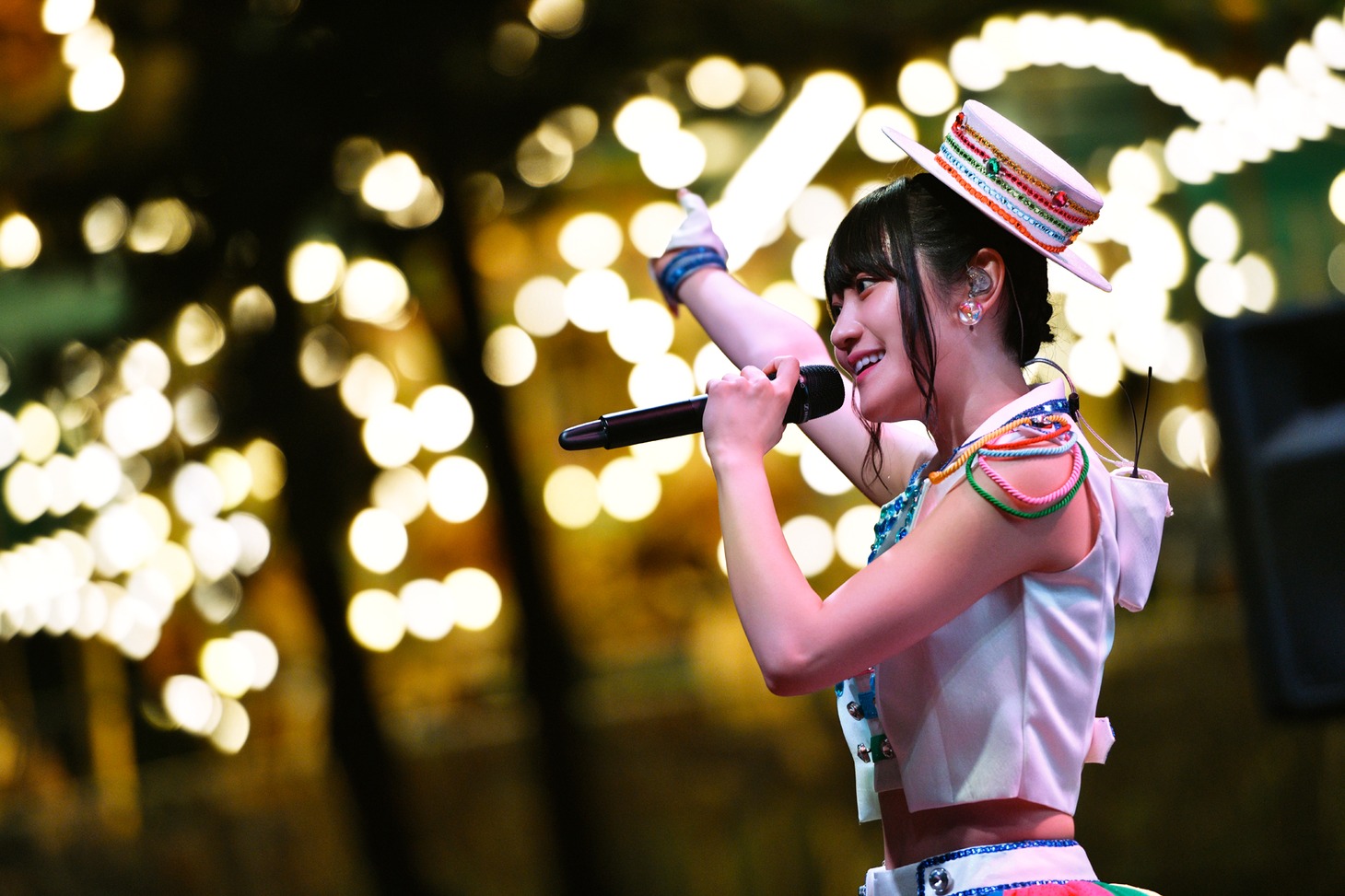 回転するメリーゴーランドの横で歌う小倉唯。