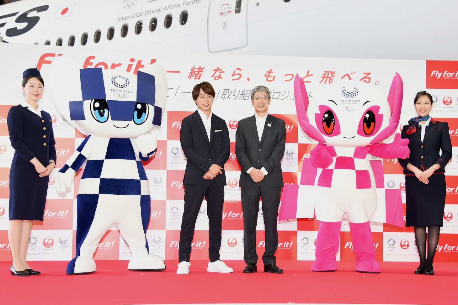 左から1964年の東京オリンピック当時の制服を着用した日本航空CA、東京2020マスコットのミライトワ、櫻井翔、赤坂祐二・日本航空代表取締役社長、東京2020マスコットのソメイティ、現行の制服を着用した日本航空CA。