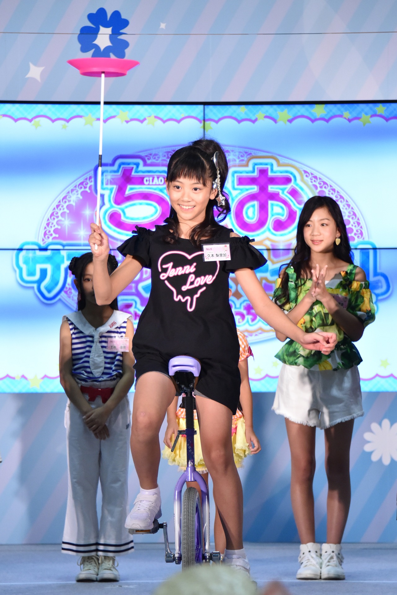 一輪車に乗って皿回しをする久本梨里加。