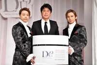 100個分の「デュオ ザ クレンジングバーム」を囲んで記念撮影するデュオ本兄弟とプレミアアンチエイジング代表取締役・松浦靖士氏（中央）。