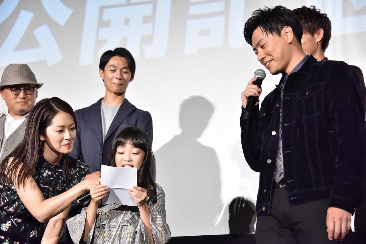 新井美羽（中央）の言葉に聞き入る山下健二郎（右）。