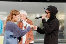 丸山桂里奈（左）の手を握って歌うHiDEX（右）と、それを冷やかすMOCA（中央）。